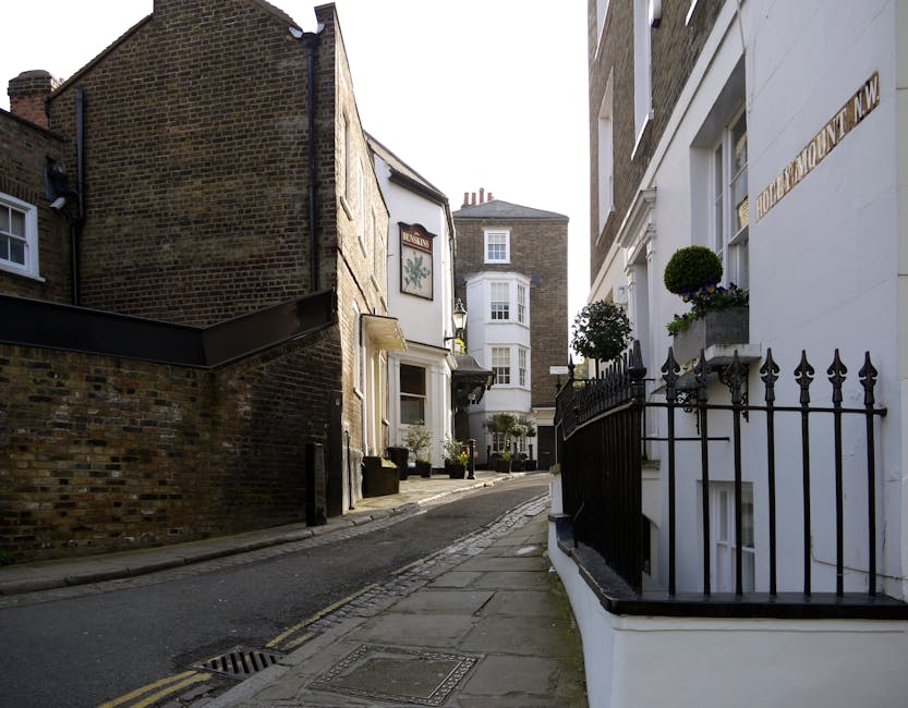 The exterior of the historic Dingwall Building in Hampstead, constructed from red bricks and featuring large arched windows on the ground floor, which are partly obscured by a black metal fence. A sig